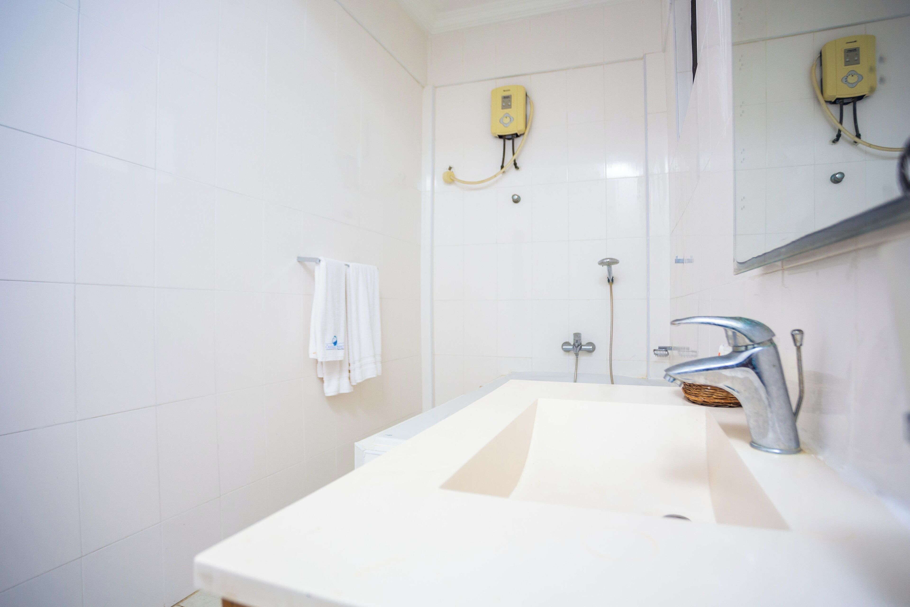 A bathroom with a white sink, a mirror, a towel rack, and a shower.