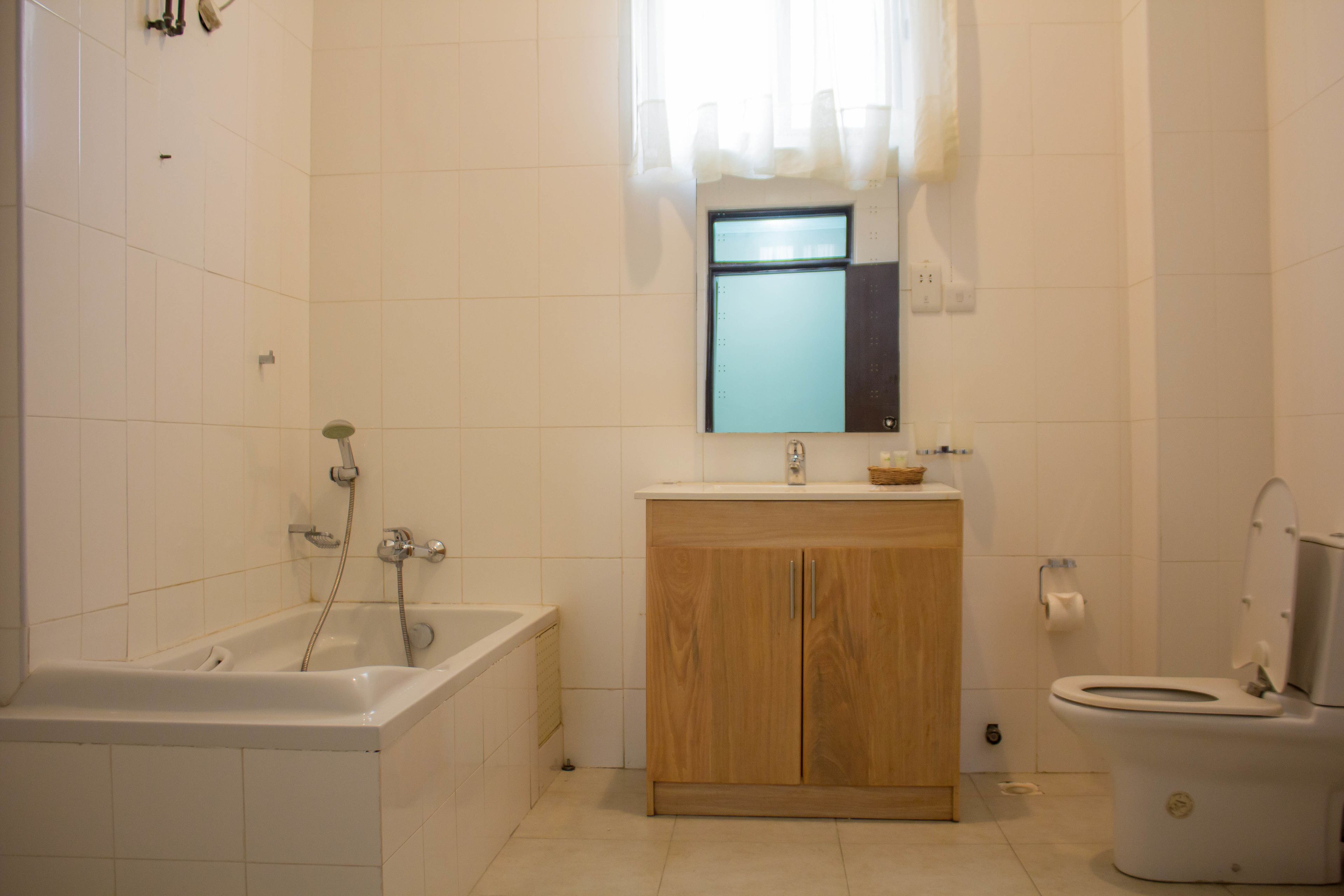 Un baño con bañera, tocador de madera y un inodoro.