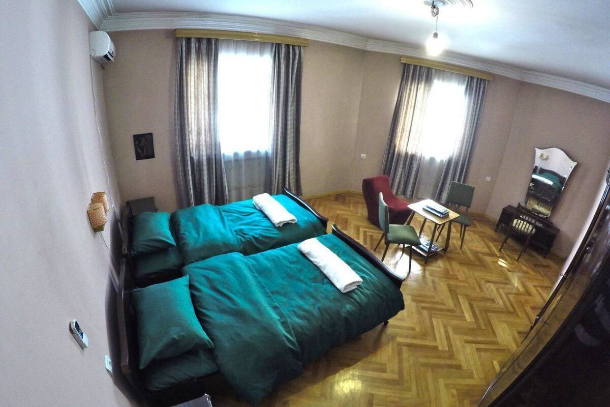 A hotel room with two beds, a desk, a chair, and a small table.