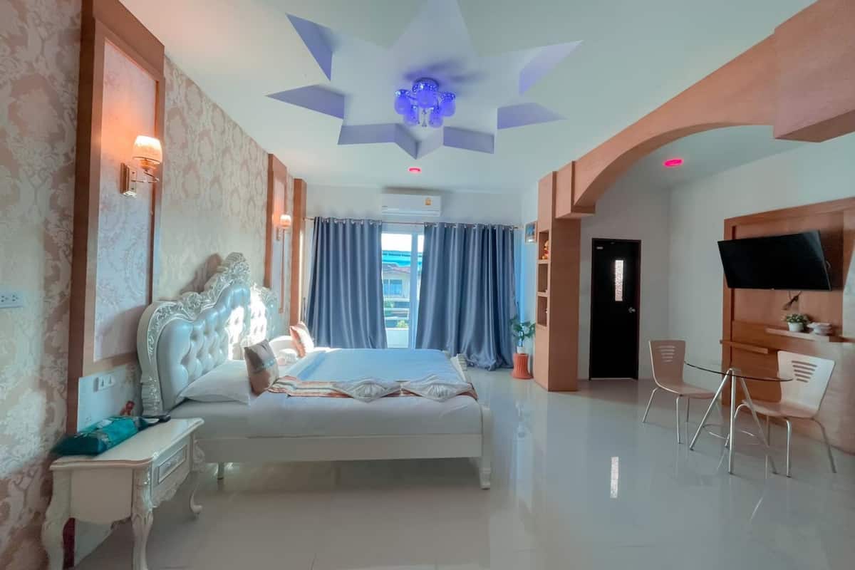 Un dormitorio moderno con una cama grande, un escritorio, una silla, un televisor y vistas al exterior.