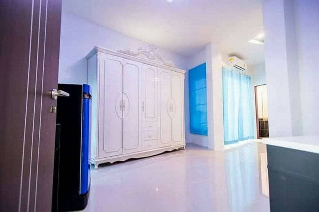 Una habitación con un armario grande de color blanco, una cortina azul y una bañera blanca.