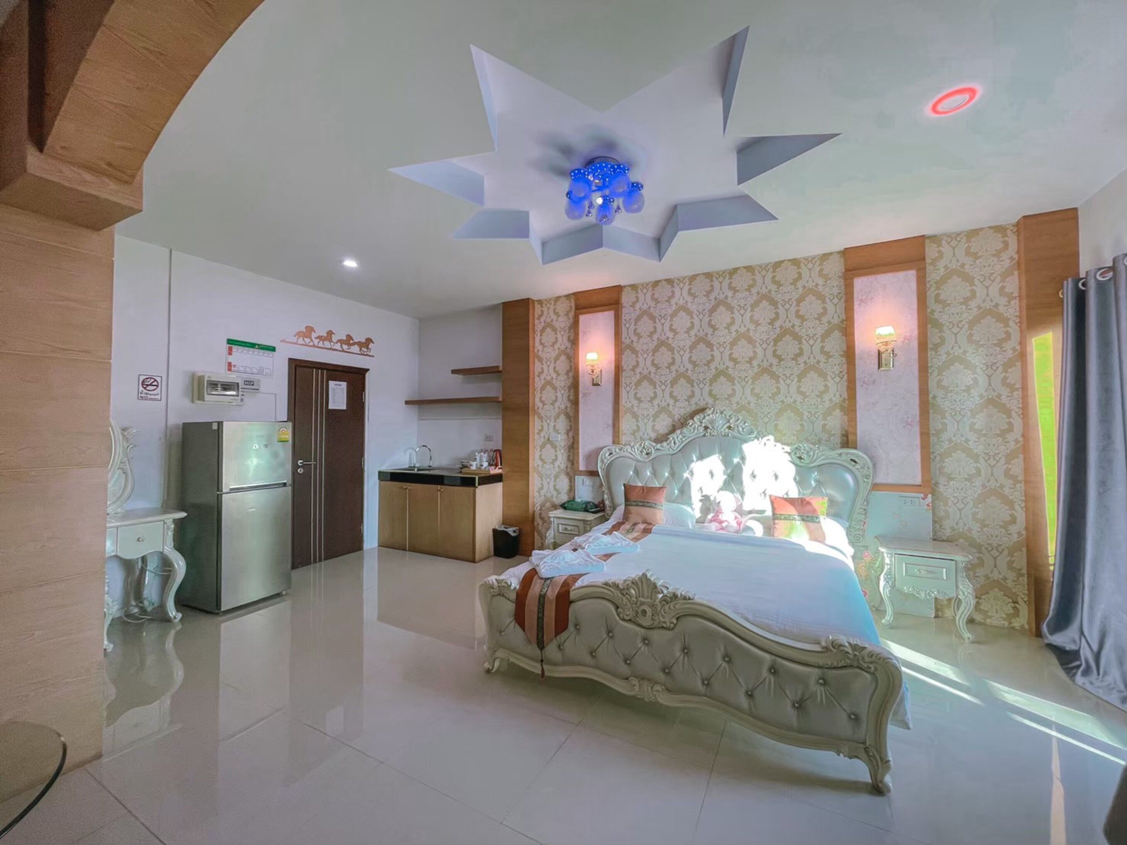 Una habitación de hotel con una cama grande, una kitchenette y un techo con diseño de estrellas.