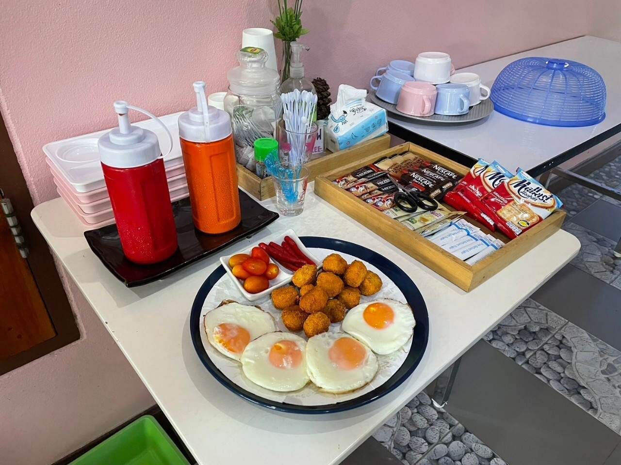 A breakfast buffet with eggs, croquettes, and various condiments.