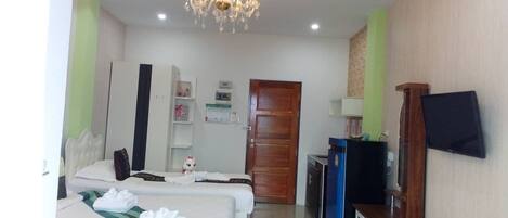 A hotel room with two beds, a television, a minibar, and a chandelier.