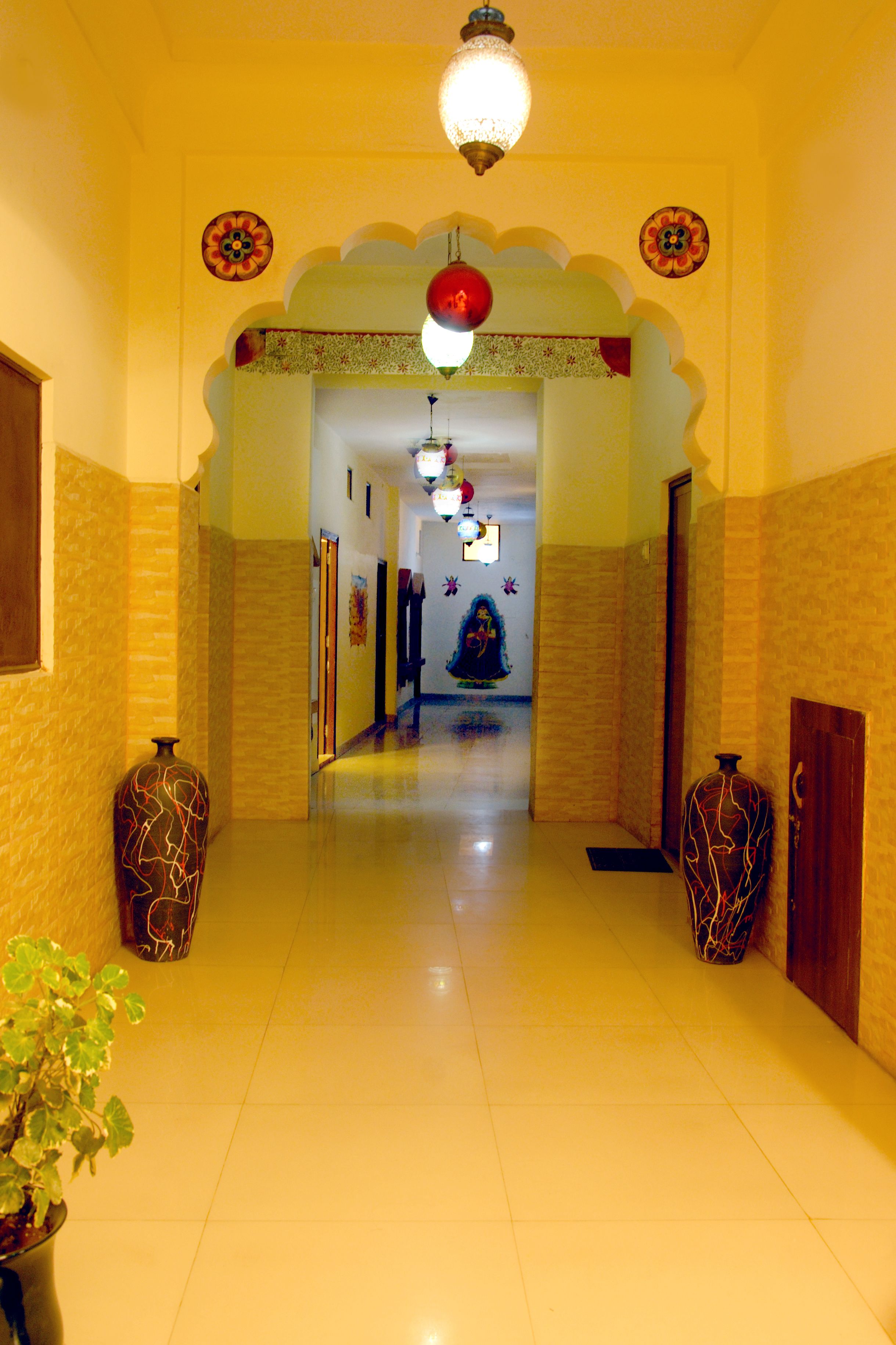 A hallway with a tiled floor, two decorative vases, a potted plant, and a ceiling light fixture.