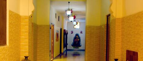 A hallway with a tiled floor, two decorative vases, a potted plant, and a ceiling light fixture.