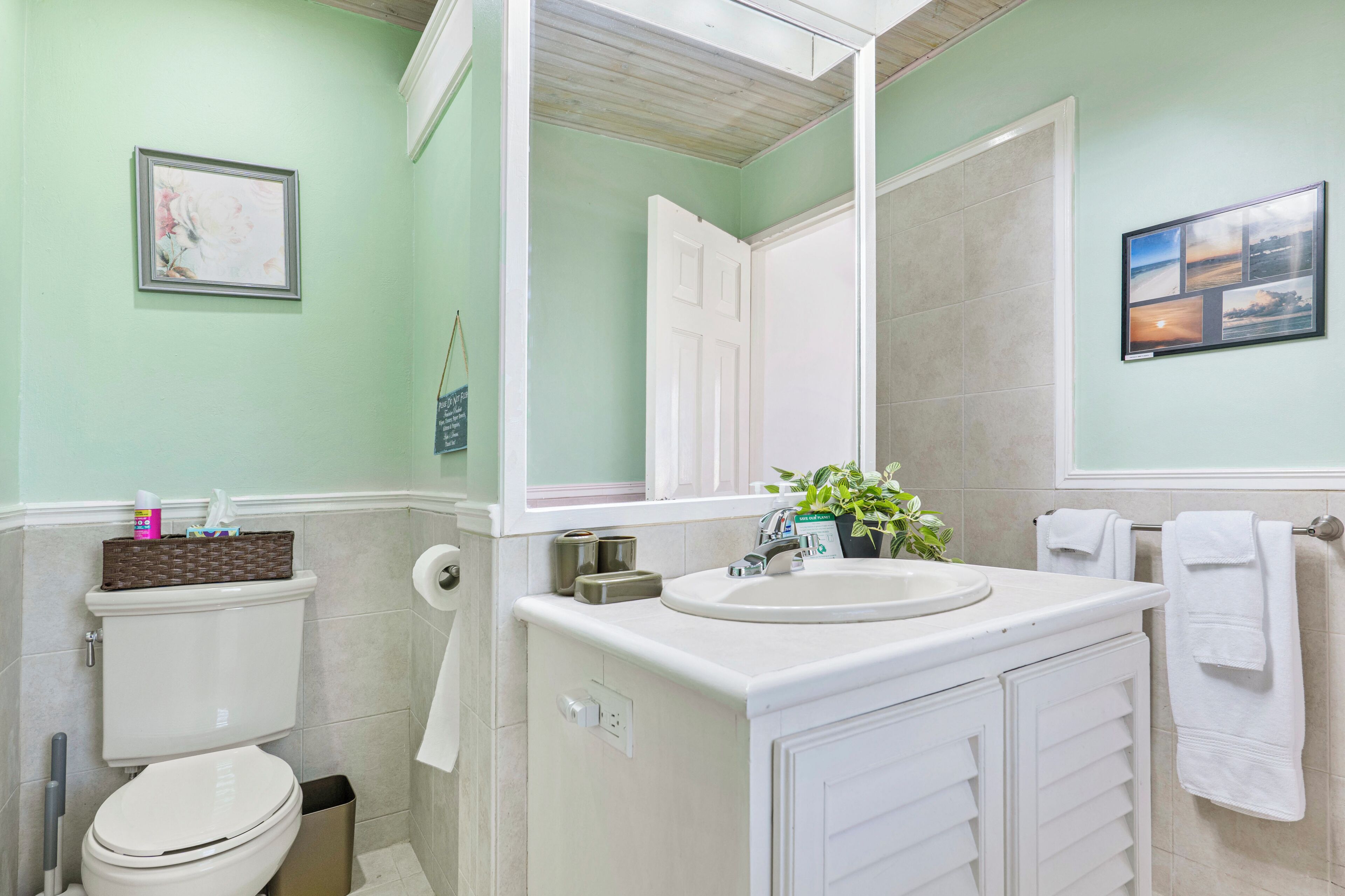 A bathroom with a toilet, sink, mirror, and towel rack.