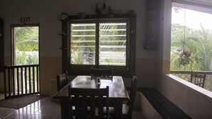 Un comedor con una mesa, sillas, una ventana con persianas y un letrero de salida.