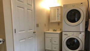 Une buanderie équipée d’un lave-linge, d’un sèche-linge, d’un évier et d’un meuble de rangement.