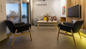 A modern living room with a sofa, two armchairs, a coffee table, and a flat-screen TV mounted on a wooden wall. - Best Seaview Attica Apartment “Sikinos” (Saronida, Athens)