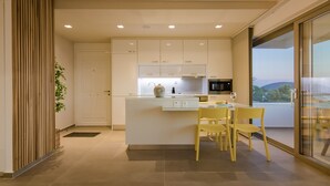 A modern kitchen with white cabinetry, a central island, and yellow chairs. - Best Seaview Attica Apartment “Sikinos” (Saronida, Athens)