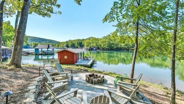 A lakeside deck with Adirondack chairs, a fire pit, and a small red building. - 3 Bedrooms, 1 Flex Room, 3 Bathrooms!  Hot Tub, Wifi & Pet Friendly!  Great Getaway For Any Season! (Huddleston)
