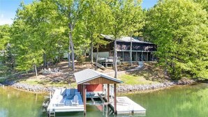A lakeside cabin with a dock, a covered seating area, and a building with a sloped roof. - 3 Bedrooms, 1 Flex Room, 3 Bathrooms!  Hot Tub, Wifi & Pet Friendly!  Great Getaway For Any Season! (Huddleston)