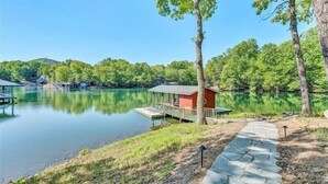 A lakeside cabin with a dock, surrounded by trees and a clear sky. - 3 Bedrooms, 1 Flex Room, 3 Bathrooms!  Hot Tub, Wifi & Pet Friendly!  Great Getaway For Any Season! (Huddleston)