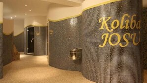 Un pasillo de hotel con paredes a cuadros y un pilar cilíndrico con la inscripción 'Koliba JOSU'.