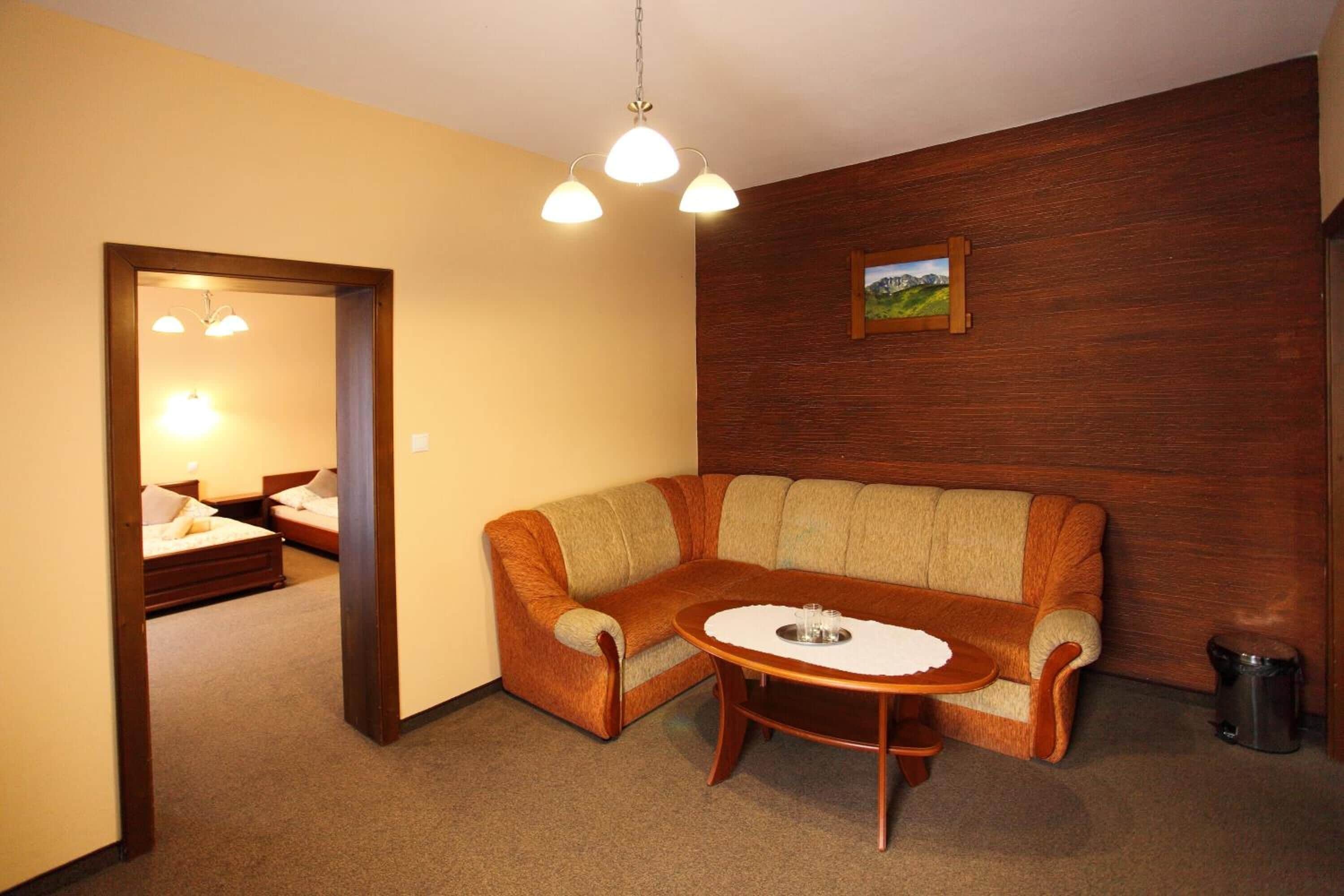 A cozy room with a wooden sofa, a round table, and a painting on the wall.