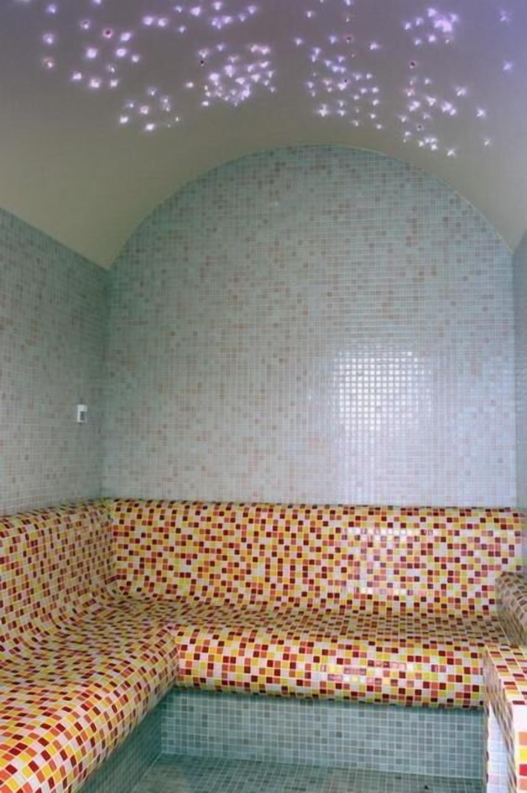 Una habitación con pared de mosaicos y un banco a cuadros.