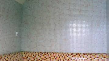 Una habitación con pared de mosaicos y un banco a cuadros.