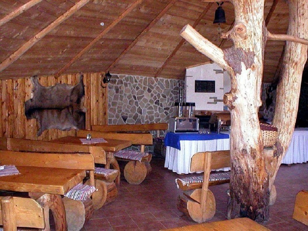 Interior rústico de madera con bancos y pared de piedra.