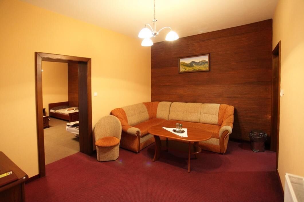 Un salon avec un mur en bois, un canapé, une petite table et une chaise.