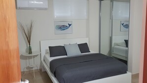 Une chambre à coucher moderne avec un lit, une petite table de chevet et un vase contenant des plantes séchées.