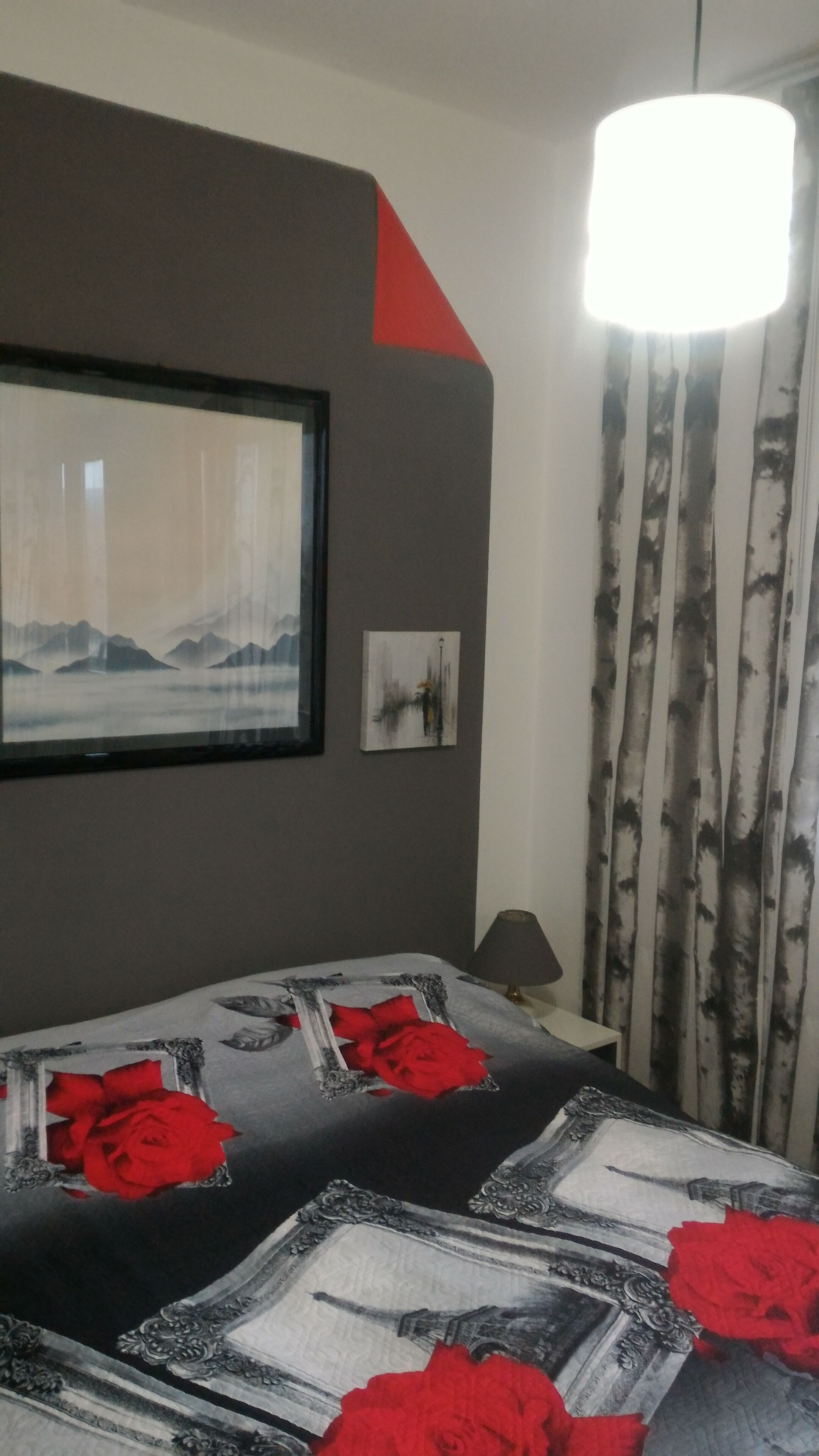 Habitación de hotel con cama, un cuadro en la pared, una lámpara y una cortina.