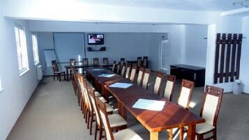 A conference room with a long table and chairs, a television, and a whiteboard.
