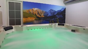 A hot tub with a green light, a mountain landscape mural, and a sliding door. - Chaty Josu Zuberec (Zuberec)