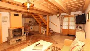 A cozy living room with a fireplace, wooden beams, a staircase, a TV, and a sofa. - Chaty Josu Zuberec (Zuberec)