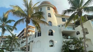 Un hotel de diverses plantes amb façana corbada, balcons i palmeres.