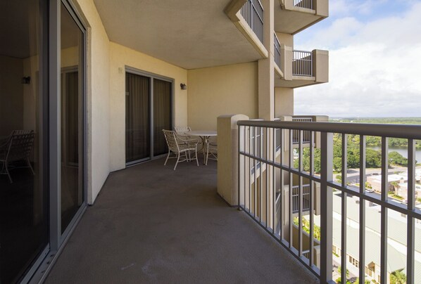 A balcony with a table and chairs, a sliding glass door, and a view of a green landscape and water. - Ocean View Luxury Condo in Royale Palms, Kingston Plantation, Myrtle Beach SC (Myrtle Beach)