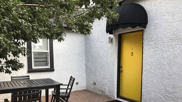 A patio with a table and chairs, a yellow door with the number 3, and a window with blinds. - Downtown Cozy Condo- Walk to Best Diners, Breweries, NAU, Historic Flagstaff! (Flagstaff)
