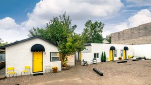 A courtyard with a white building featuring yellow doors, brick flooring, and outdoor seating. - Downtown Cozy Condo- Walk to Best Diners, Breweries, NAU, Historic Flagstaff! (Flagstaff)