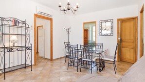 Una stanza con un tavolo da pranzo e sedie, un lampadario, uno specchio e un armadio.