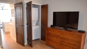 Een kamer met een houten dressoir, een televisie erboven en een wasmachine op de achtergrond.