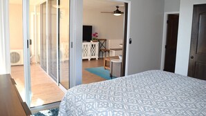 Een slaapkamer met een bed, een schuifdeur naar een balkon en een plafondventilator.