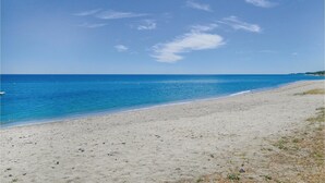 Une plage avec une eau d’un bleu limpide et un rivage sablonneux.