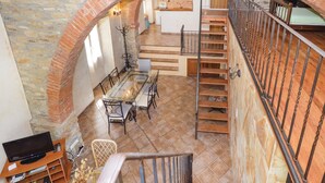 Un appartement spacieux de style « loft », comprenant un coin repas, une cuisine et un escalier menant à un niveau supérieur.