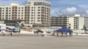 A beachfront hotel with multiple balconies and a sandy beach area.