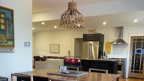 Eine moderne Küche mit Holzboden, einem Esstisch mit Stühlen, einer Pendelleuchte und einem Kühlschrank.
