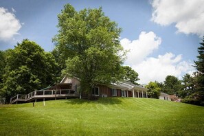 Une propriété résidentielle dotée d’un grand arbre, d’un porche abrité et d’une pelouse bien entretenue.