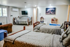 A bedroom with two beds, a sofa, a TV, and a painting.