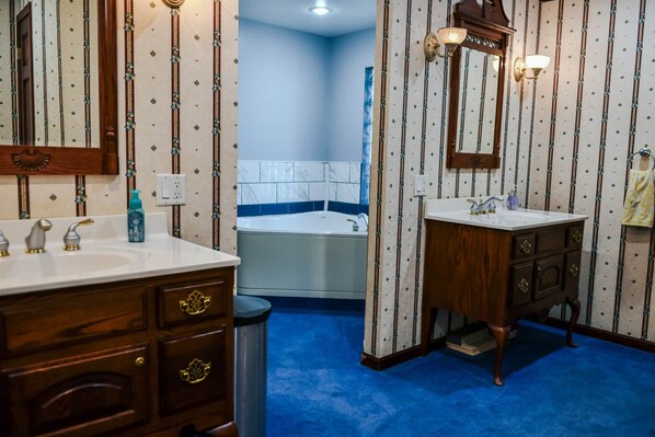 A bathroom with a bathtub, two sinks, and a vanity with drawers.