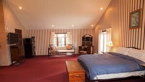 Een slaapkamer met een bed, een bankje, een stoel, een bureau en een televisie.