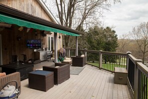 A deck with outdoor furniture, a grill, and a TV screen.