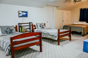 A dormitory room with two wooden beds, a bookshelf, and a ceiling fan.