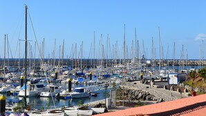 Un port de plaisance où sont amarrés de nombreux bateaux, un mur de pierre et un ciel bleu azur.