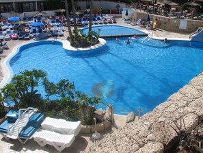 Une grande piscine dotée de plusieurs couloirs, entourée de chaises longues et de parasols.