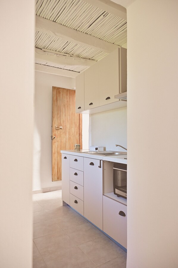 Une cuisine moderne avec des armoires blanches, une porte en bois et un évier en acier inoxydable.