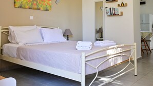 A bedroom with a bed, a bedside table, a lamp, a painting, and a ceiling fan. - The Papas House on the Hill (Kamilari)